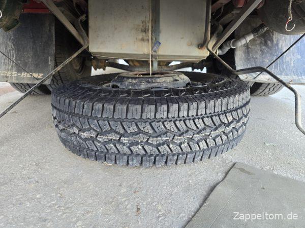 Ersatzrad mit neuem Reifen unter dem Bus